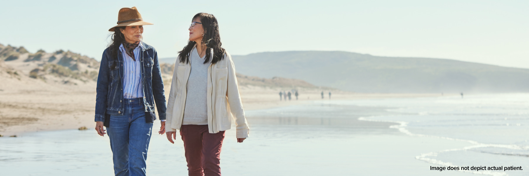 Two women walking along beach together